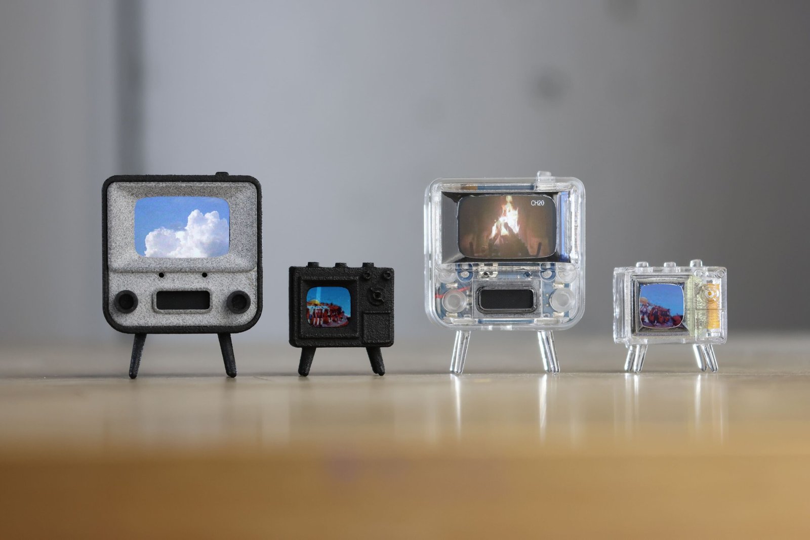 Four TinyCircuits miniature TVs, including the TinyTV 2, displayed side by side on a tabletop.