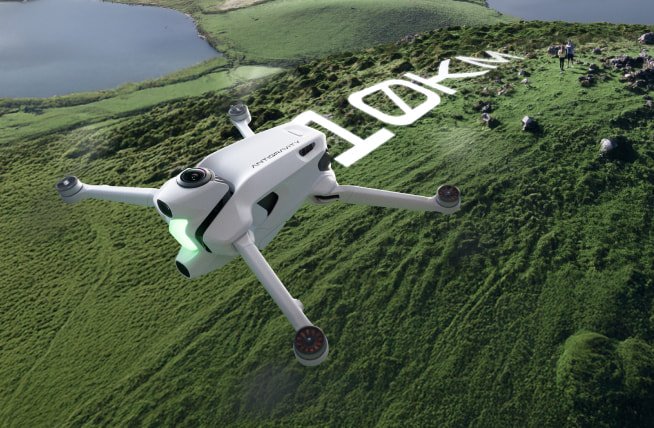 A sleek white futuristic drone labeled “A1 Antigravity Drone” hovers over a lush green landscape near a lake. The drone emits a soft green light, and the word “LOOK” is projected or displayed on the ground below it. Two small figures stand in the distance among rocks on the grassy terrain.